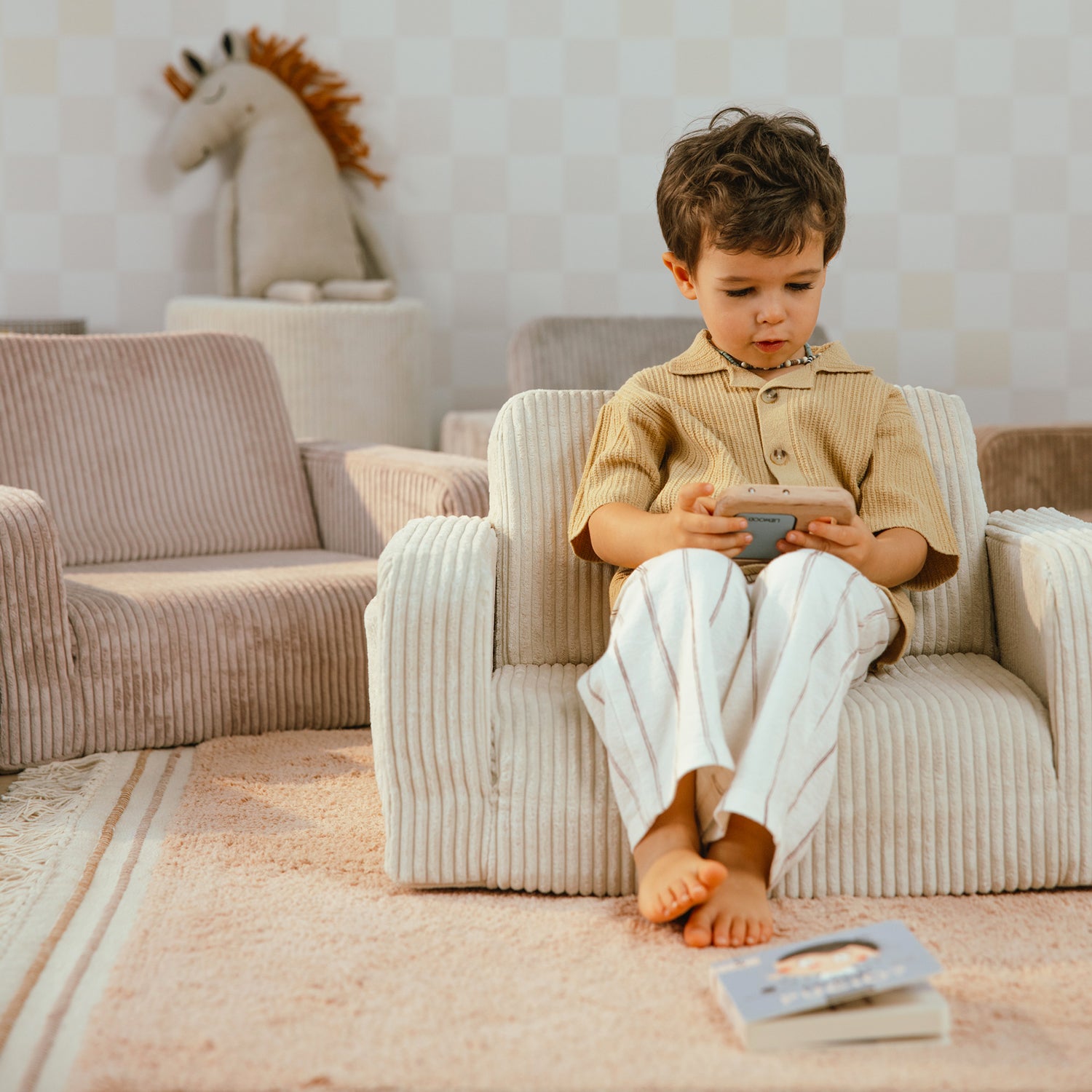 Garçon assis confortablement dans un fauteuil enfant velours vanille