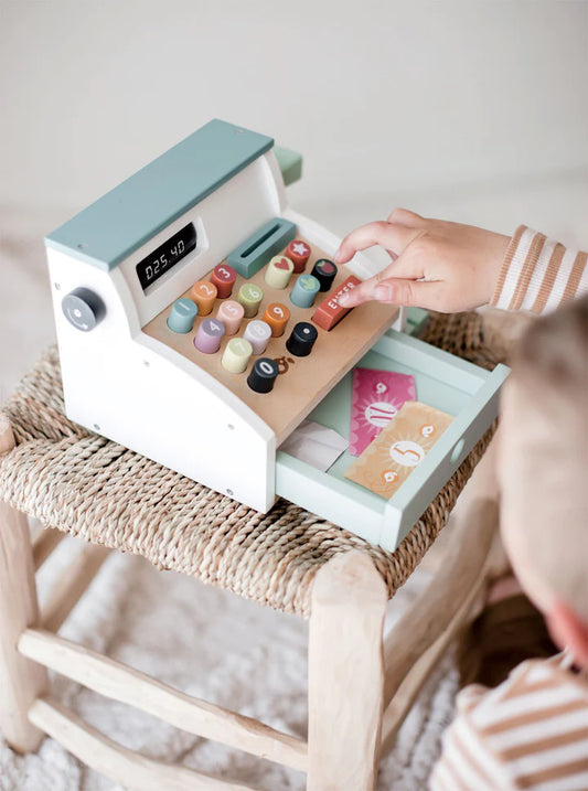 Jouet d'imitation mixte, fille ou garçon adorent jouer au marchand ou à la marchande. Ici un petit garçon ouvre le tiroir-caisse dans lequel sont rangés des billets et quelques pièces.