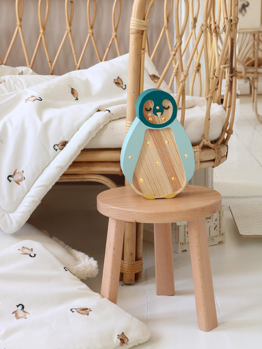Lampe veilleuse pingouin posée sur une table de nuit enfant