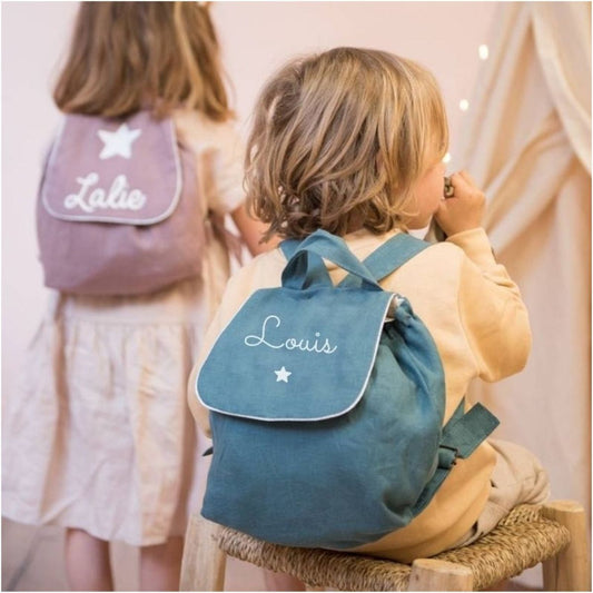 Idée cadeau de naissance personnalisée.Enfant portant un sac à dos bébé crèche en lin bleu canard, prénom personnalisé