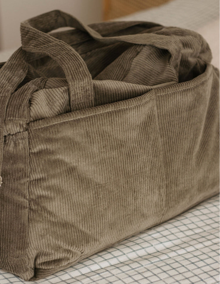 Sac à langer vert kaki, en velours. Pratique avec poches intérieures et extérieures.