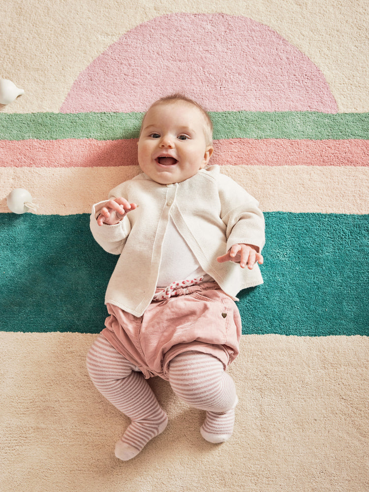 Tapis pour chambre bébé en coton biologique certifié GOTS. Bleuu-studio. Motif coucher de soleil rose et vert, sur fond beige. Doux et confortable. Facile à entretenir.