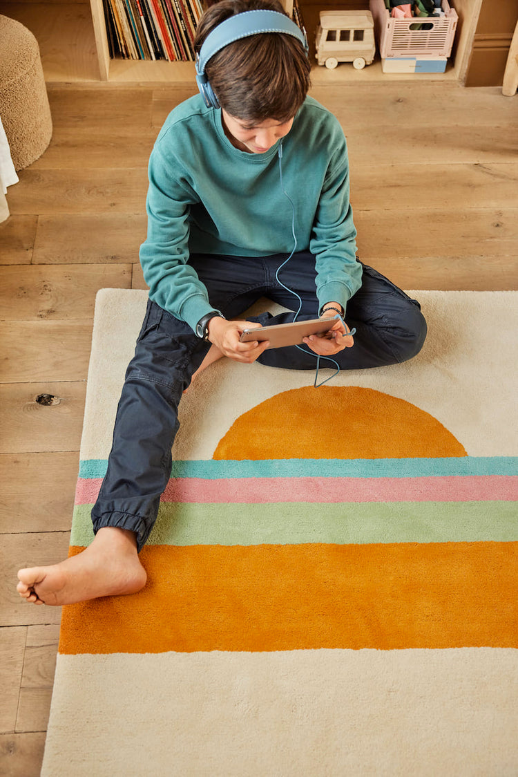 Tapis pour enfant coloré et lumineux. Coucher de soleil orange vert bleu rose sur fond beige. Idéal pour décorer chambre garcon ou fille. Deux tailles disponibles. Bleuu-studio.