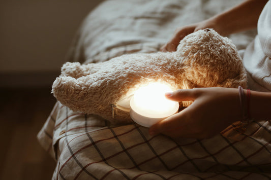 Peluche ourson avec module lumineux intégré dans la peluche. Avec 7 positions lumineuses différentes, pour s'adapter au sommeil de bébé. Recharge facile. Autonomie 8 h en fonctionnement. Moonie, spécialiste de la peluche sommeil pour bébé.