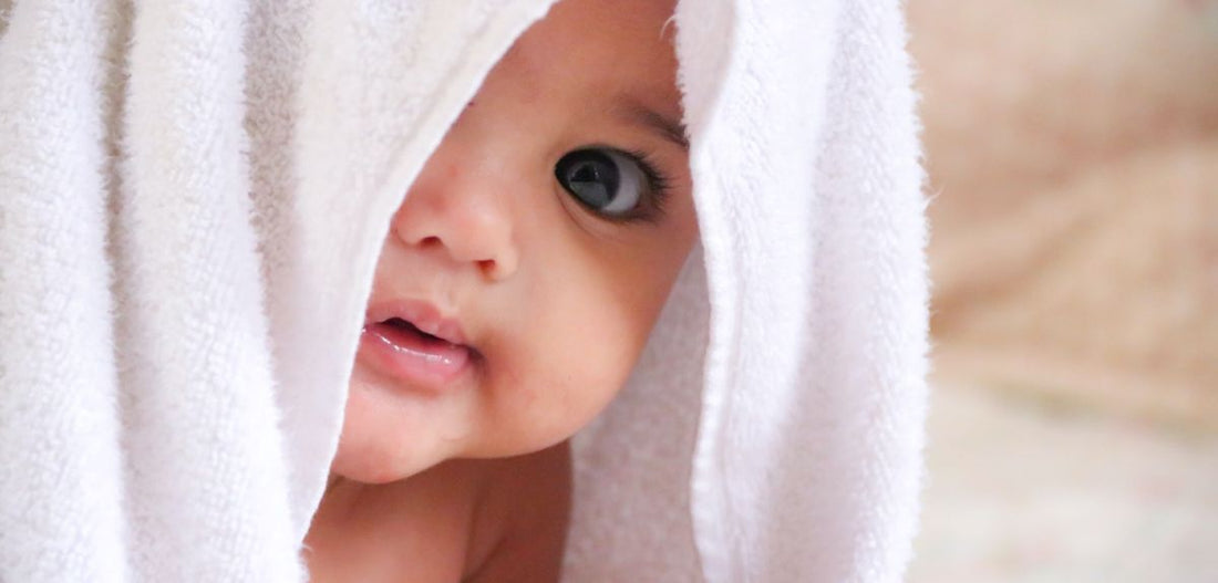 Bébé caché sous une serviette de bain blanche