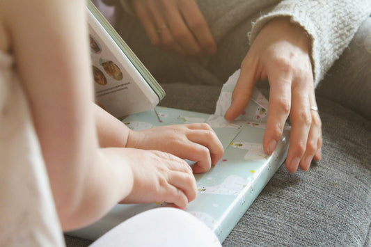 Inspirations de petits mots pour accompagner un cadeau pour bébé. Crédit photo Sigmund sur Unsplash : enfant et adulte déballant un paquet cadeau ensemble. 