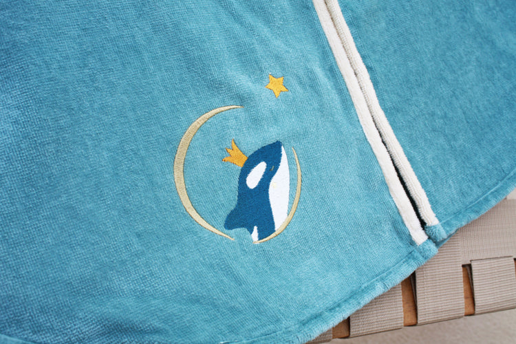 Détail broderie orque sur cape de bain bébé bleue personnalisée prénom brodé