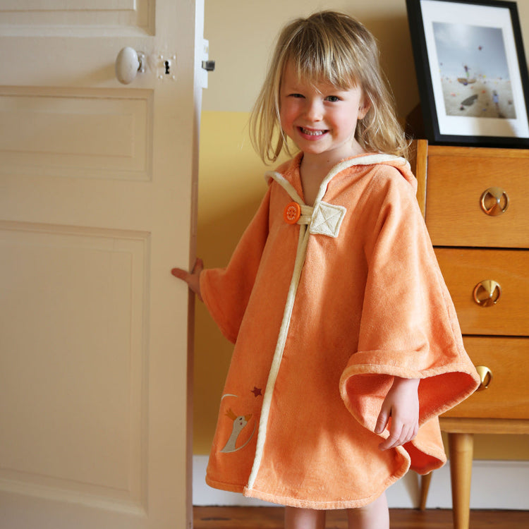 Cape de bain bébé jaune orange personnalisée prénom brodé portée par un enfant à la maison