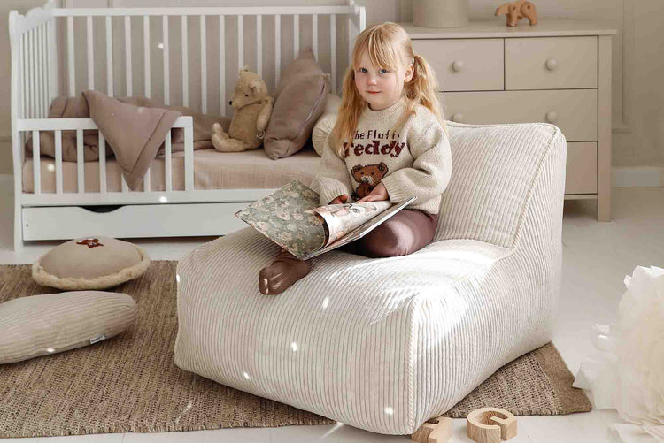 Enfant installé dans un fauteuil Kumo Shappy beige vanille pour créer un coin lecture confortable