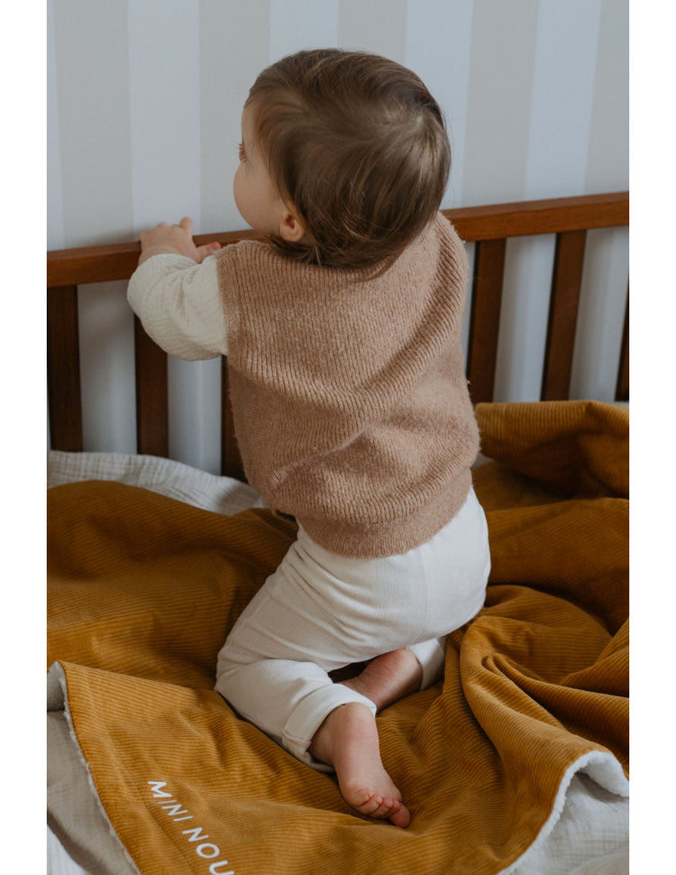 Couverture bébé personnalisée en velours moutarde, ambiance chambre, douce et chaude pour l’automne-hiver.