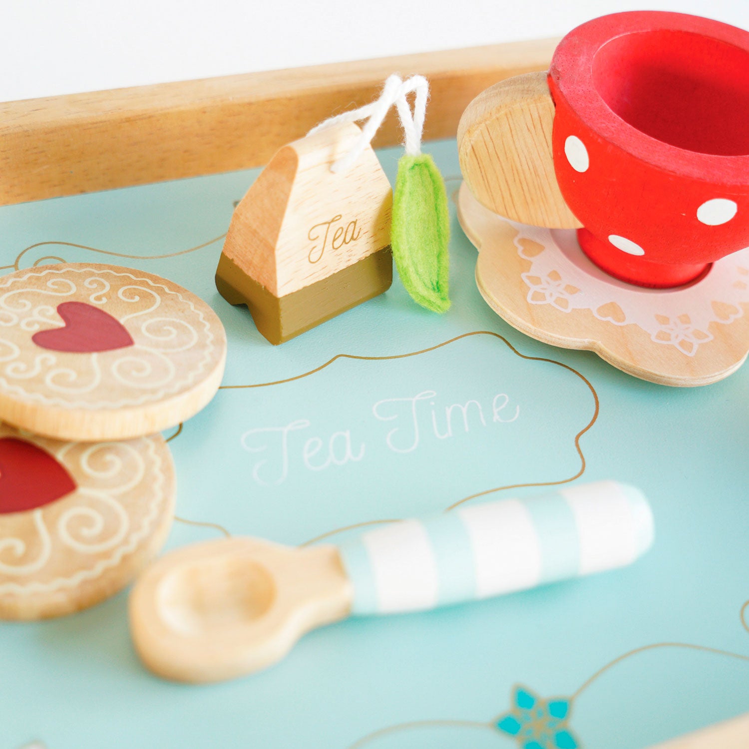 Jouet dinette en bois Le Toy Van. Plateau en bois peint en bleu avec inscription Tea Time. Biscuits formes rondes, dessins légers arabesques blancs et coeur rouge. Cuillère à rayure blanche et bleu. Tasse vintage rouge à pois blancs. 