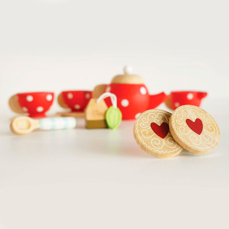 Zoom sur les 2 biscuits aux formes rondes et dessins coeur rouge, inclus dans le service à thé pour enfant en bois.