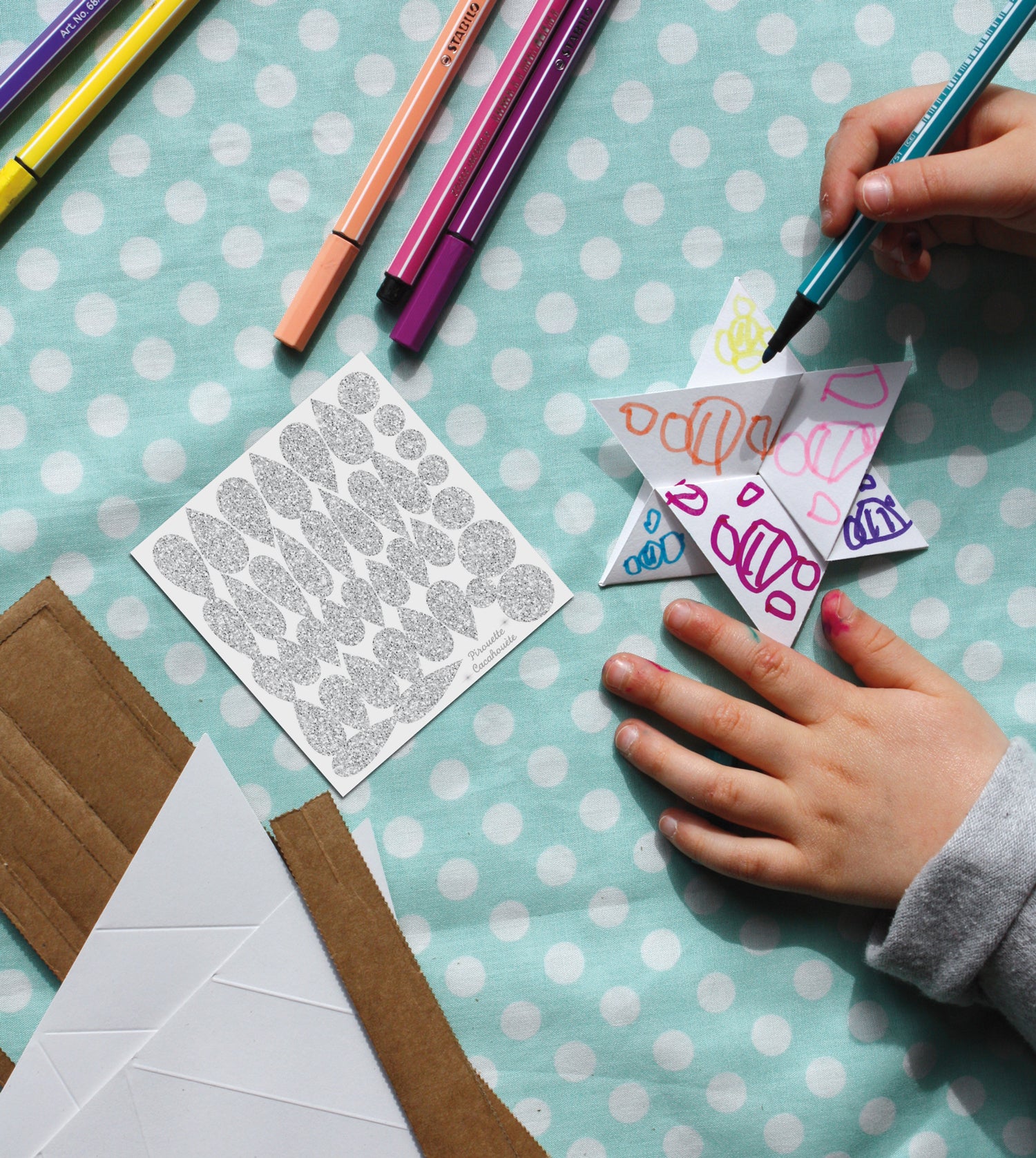 Dès 5 ans, votre enfant peut fabriquer et personnaliser sa baguette magique selon ses envies comme ici où un enfant dessine des formes au feutre en plus des stickers brillants qu'il collera sur l'étoile de sa baguette magique en carton.