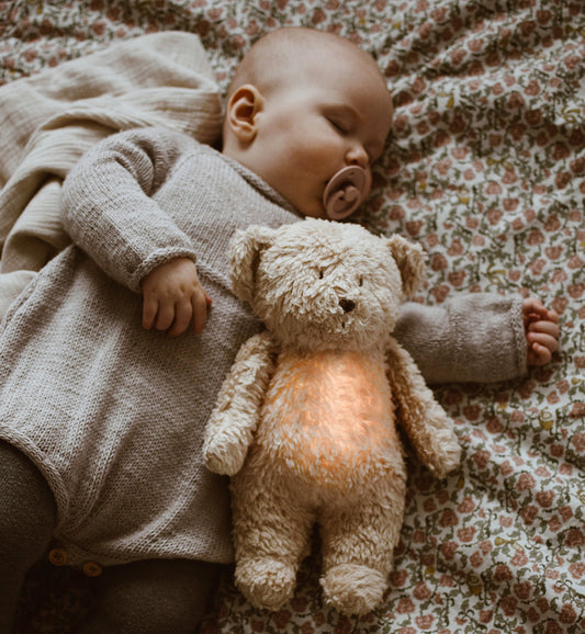 Peluche veilleuse ourson avec lumière douce et bruits blancs. Idéal pour endormir bébé. Avec capteur de pleurs et déclenchement automatique dès que bébé se réveille la nuit. Ourson magique Moonie.