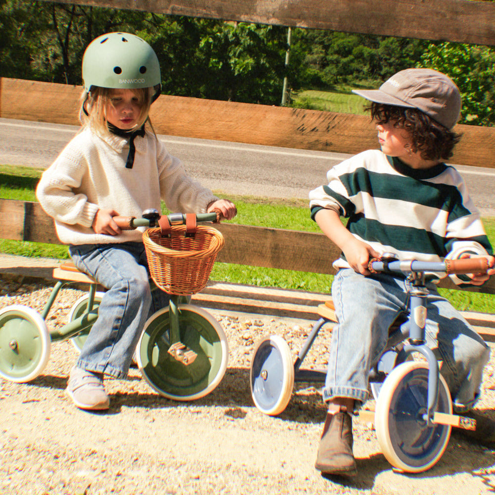 Enfants jouant en extérieur avec des tricycles vintage Banwood