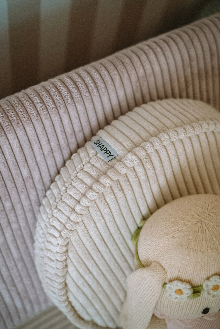 Détail du logo Shappy sur le coussin rond du fauteuil chauffeuse enfant en velours côtelé pastel