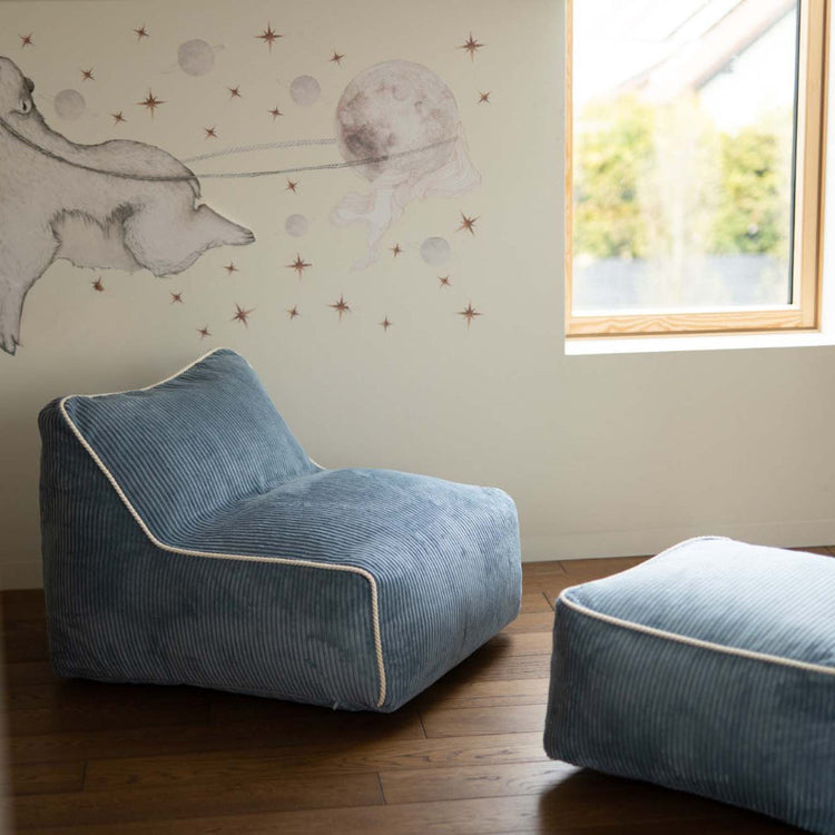 Fauteuil enfant bleu velours, modèle Kumo avec pouf dans une chambre cosy. Made in Europe.