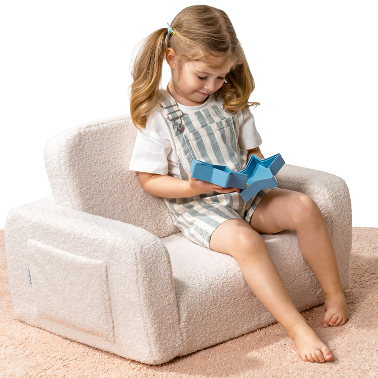 Enfant assis dans un fauteuil enfant moumoute design avec accoudoirs confortables.