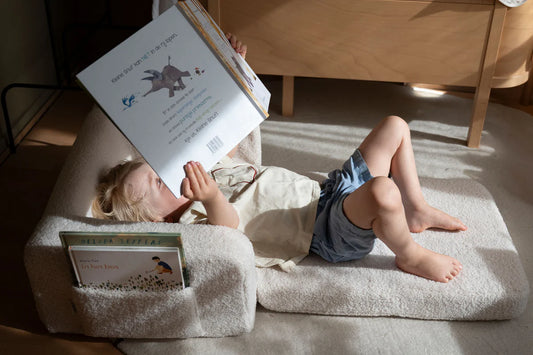 Enfant lisant un livre confortablement installé dans un fauteuil enfant moumoute modulable.
