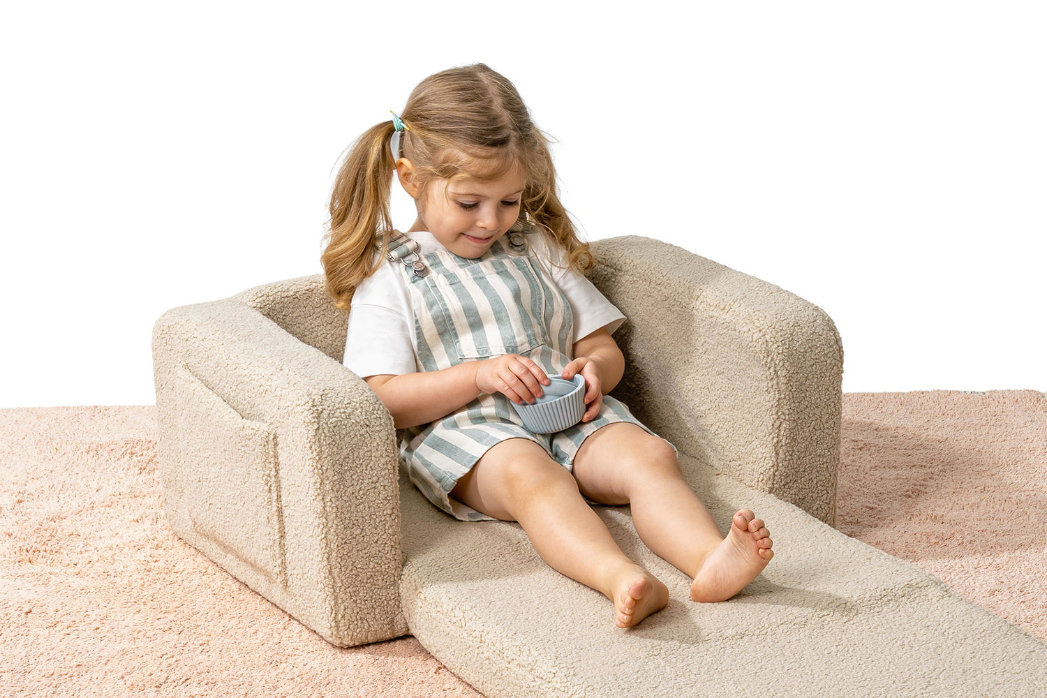Enfant confortablement installé dans un fauteuil lecture enfant beige.