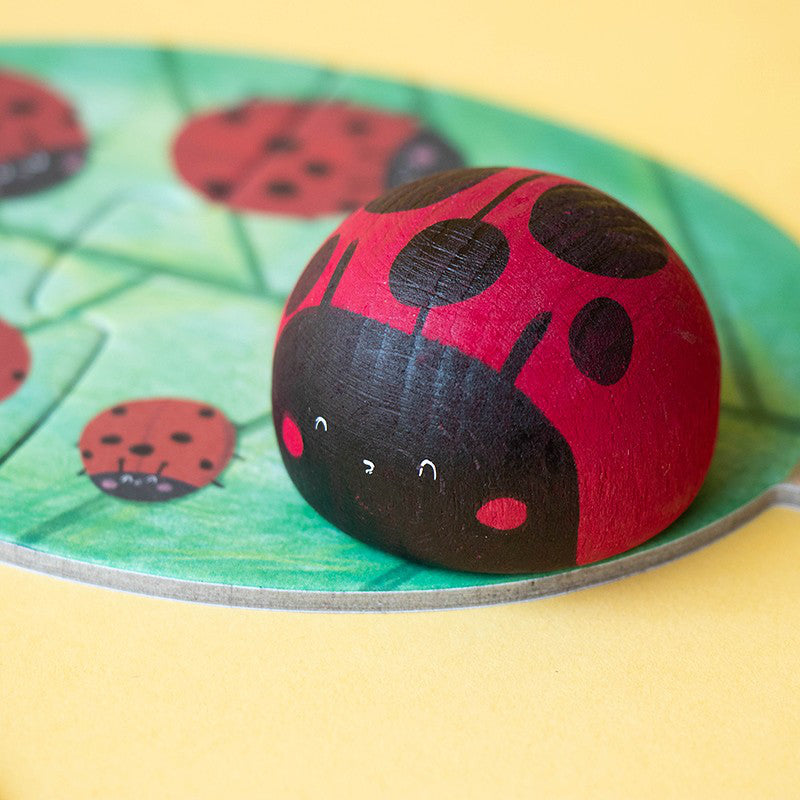 Gros plan sur la figurine coccinelle en bois peint et son petit sourire tout doux