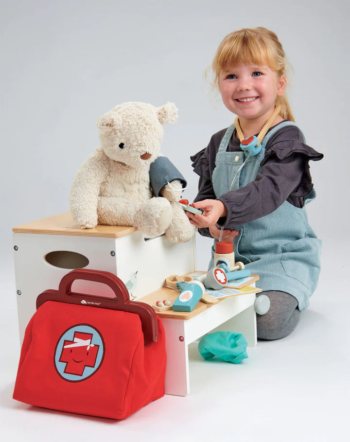 Panoplie de docteur, jouets en bois et en tissu. Petite fille qui joue à prendre la tension de son nounours pour le soigner. 