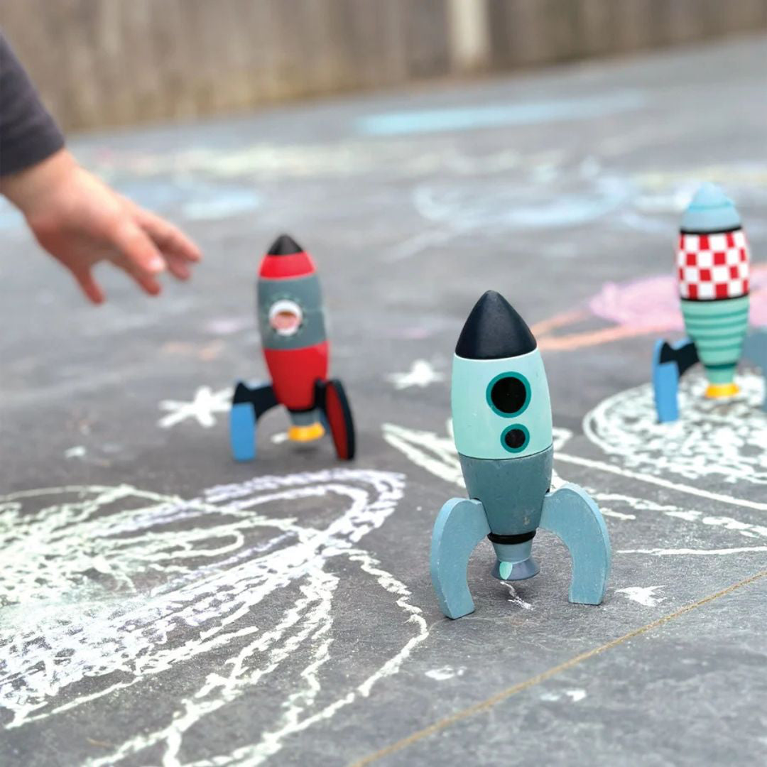Enfant attrapant une fusée en bois lors d'un jeu spatial à la craie en extérieur