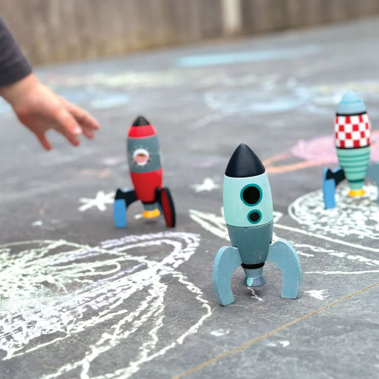 Enfant attrapant une fusée en bois lors d'un jeu spatial à la craie en extérieur