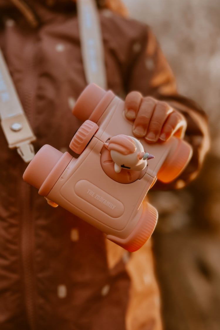 Jumelles enfant licorne design compact rose tenues par une enfant