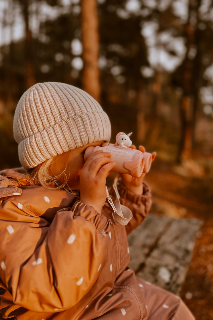 Enfant jouant avec des jumelles licorne rose pendant une balade