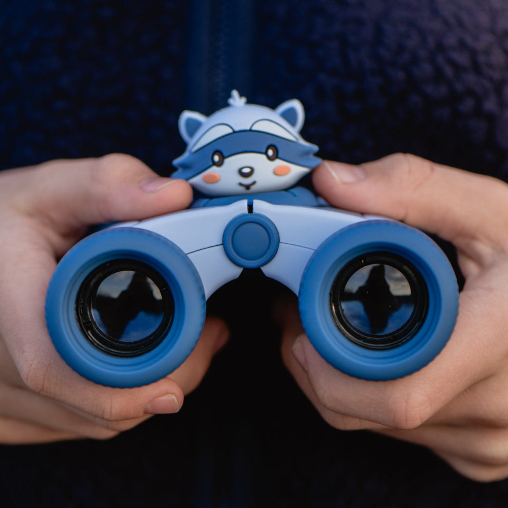 Jumelles Raton laveur The Zoo Family tenues entre les mains d'un enfant, avec leur design bleu et leurs deux objectifs