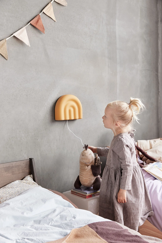 Décoration chambre enfant OYOY Mini. Lampe murale avec prise et interrupteur, pour chambre d'enfant. Jaune en forme d'arc-en-ciel. Légère en silicone.