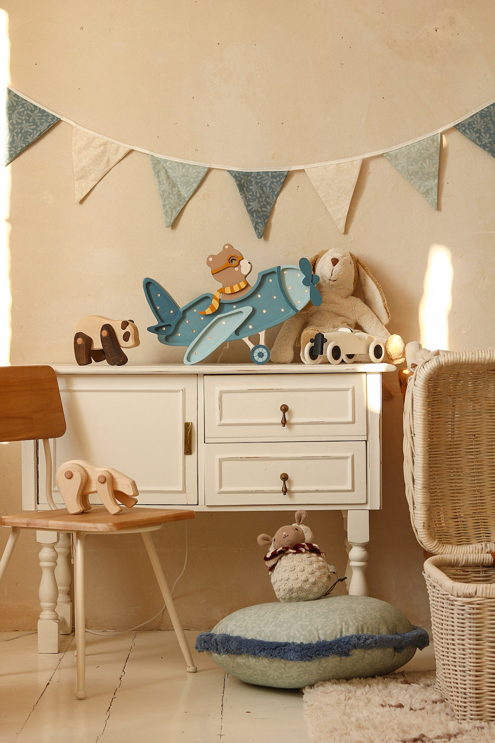 Veilleuse avion en bois ourson placée sur une commode dans une chambre de bébé. Modèle bleu. 