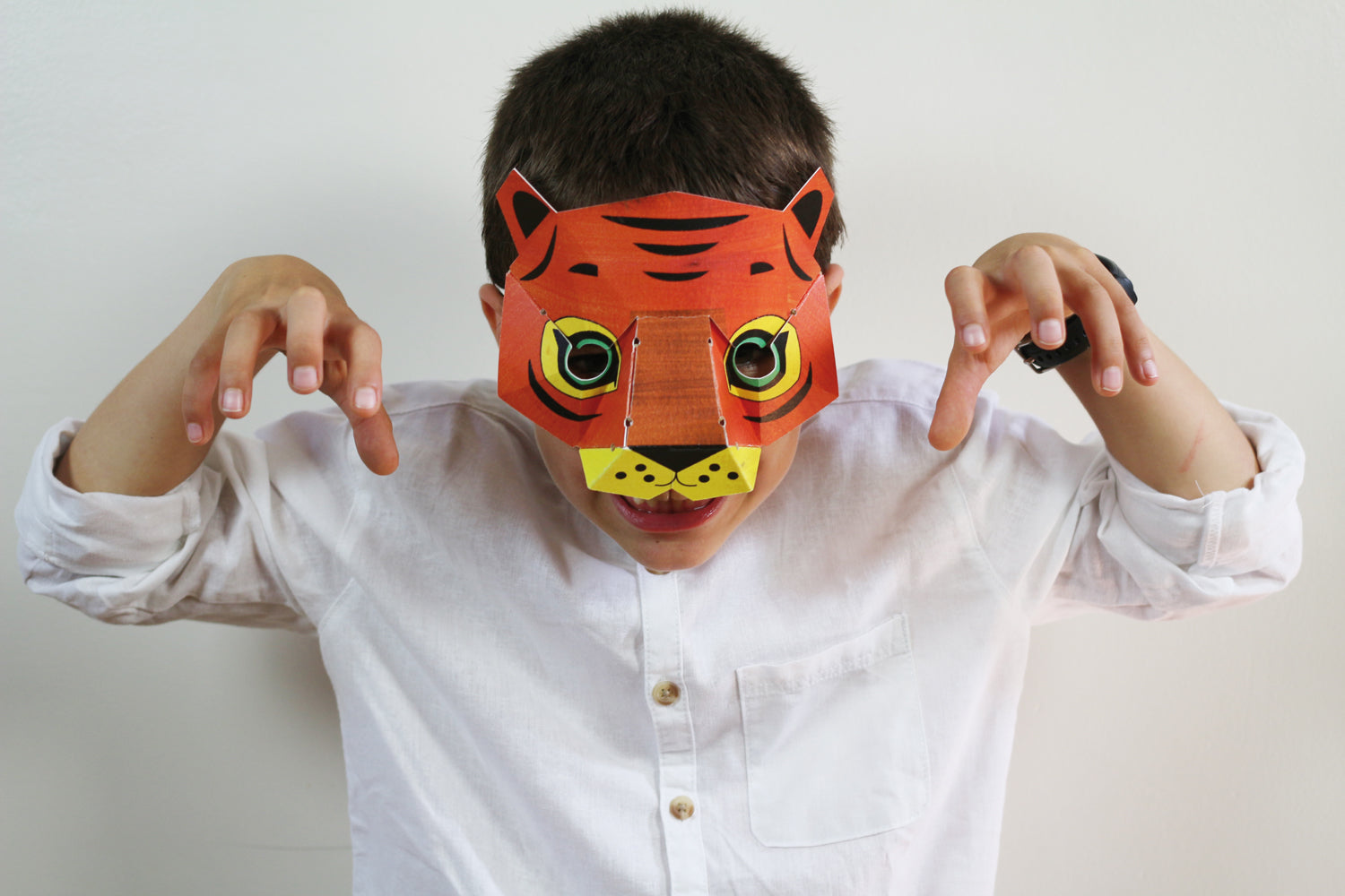 Masque à colorier en forme de tigre. Made in France. Déguisement carnaval amusant et activité créative. Sur la photo, un garçon d'environ 6 ans imite le tigre avec son masque.
