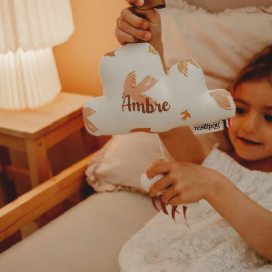 Enfant tenant un nuage musical personnalisé dans une chambre douce, rituel du coucher et cadeau naissance musical