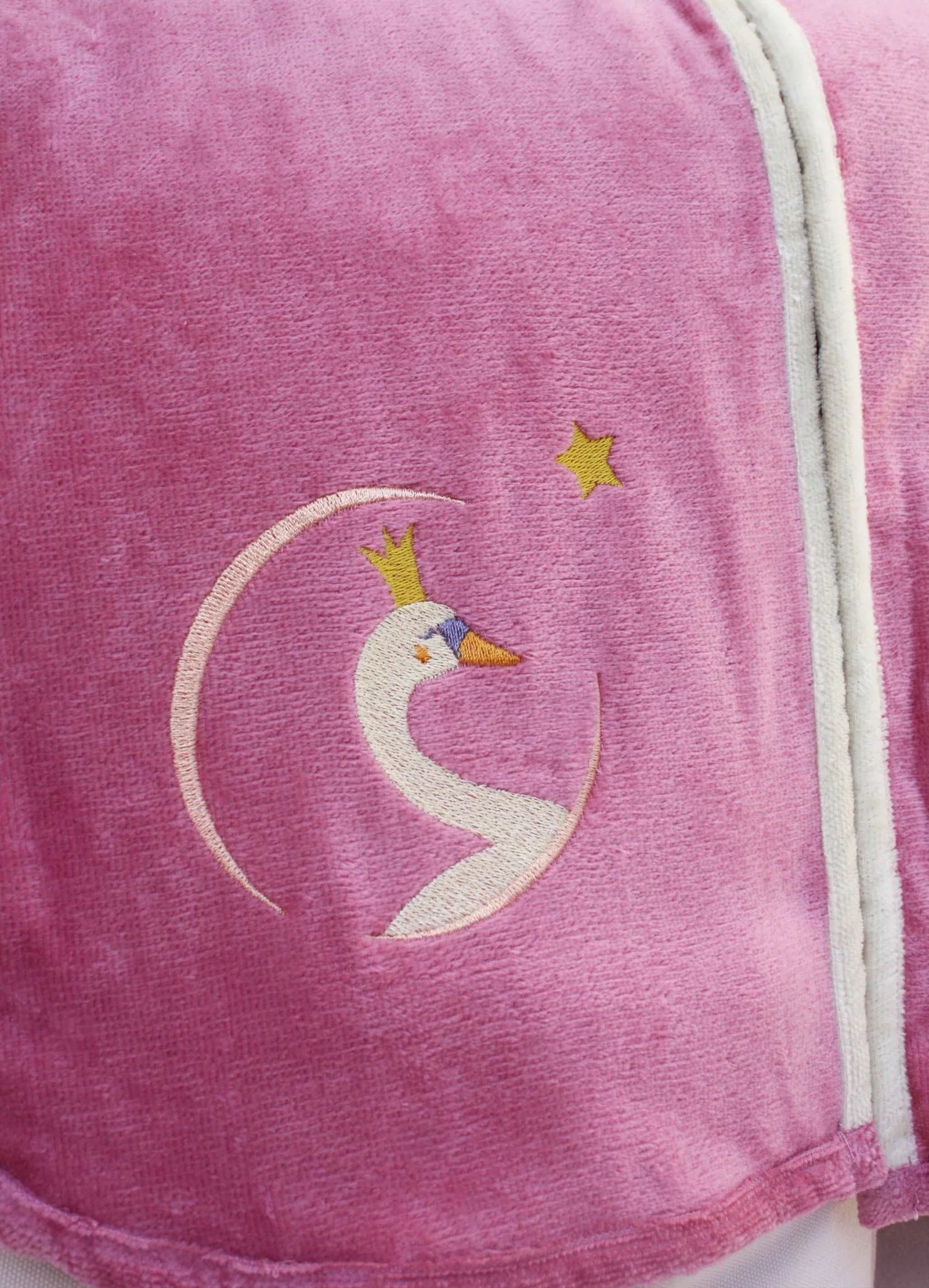 Détail broderie prénom sur peignoir enfant 2 ans personnalisé. Couleur vieux rose, motif cygne couronne.