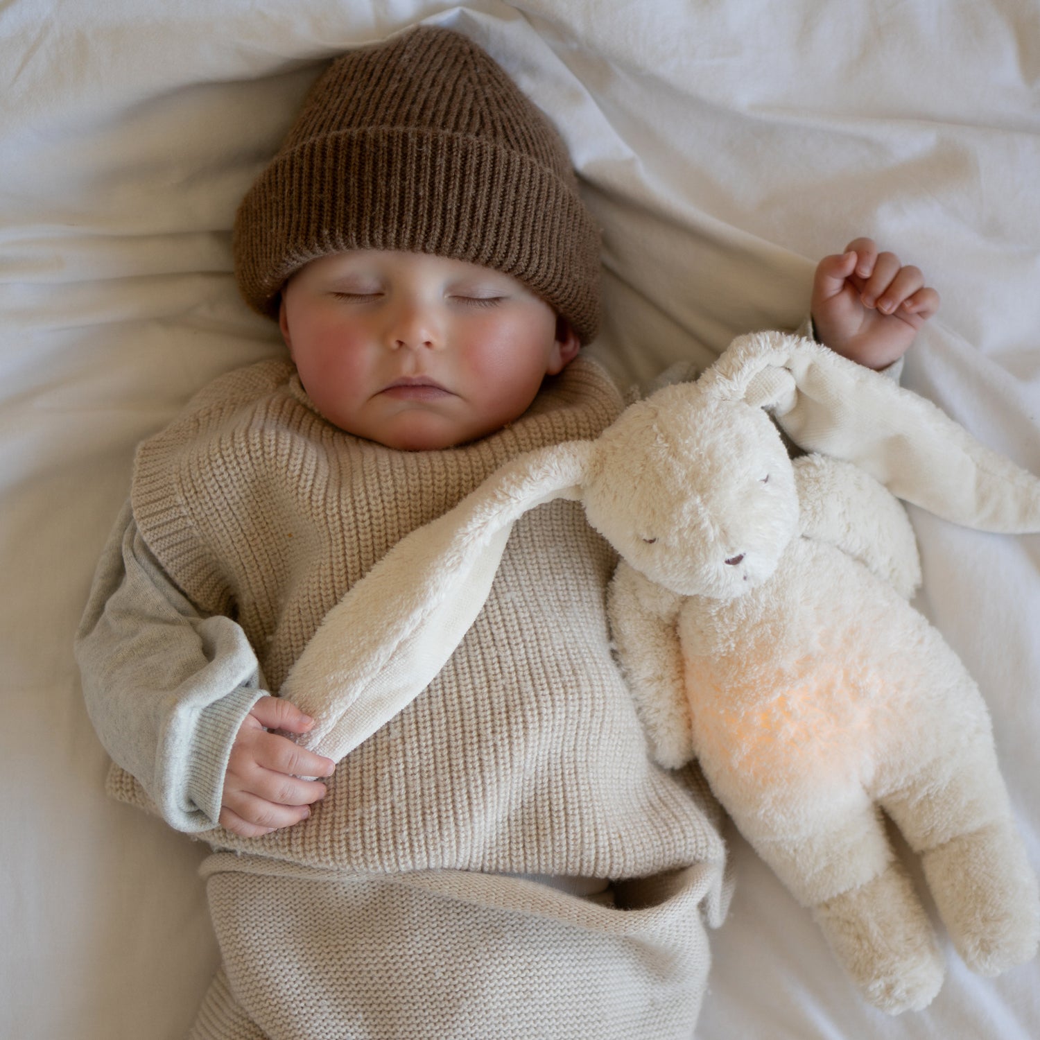 Peluche lapin veilleuse pour bébé Moonie avec bruits blancs, lumière douce et coton biologique certifié GOTS.
