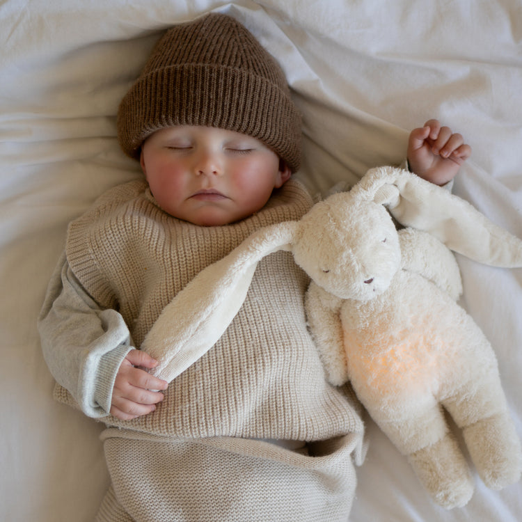 Peluche lapin veilleuse pour bébé Moonie avec bruits blancs, lumière douce et coton biologique certifié GOTS.