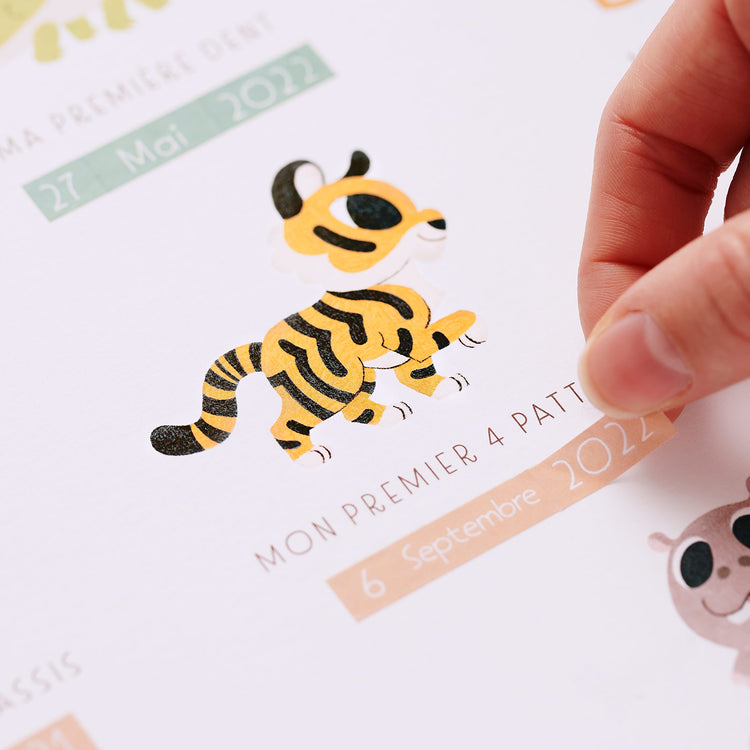 Premiers pas de bébé, illustré par un petit tigre qui marche fièrement sur ses 4 pattes. La date est ajoutée manuellement grace aux stickers autocollants fournis dans le pack. Cadeau de naissance premières fois.