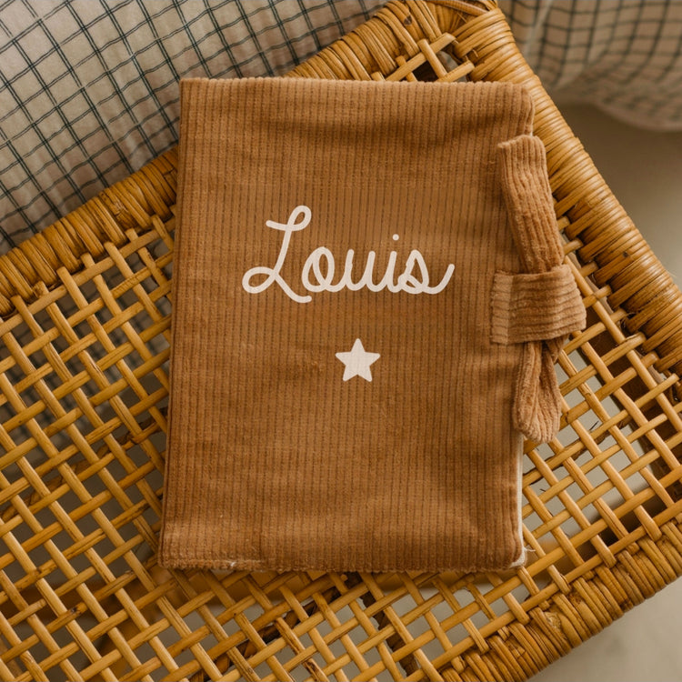 Protège carnet de santé personnalisé en velours marron clair, ambiance chambre bébé, fabrication française.