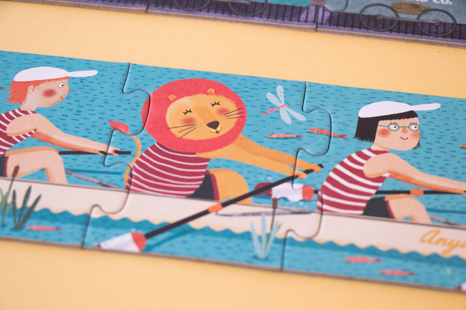 Zoom sur l'un des puzzles évolutifs du coffret où 2 enfants et 1 lion souriant pagaient sur un rameur. Londji, puzzles écoresponsables.