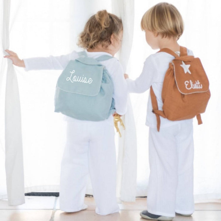 Deux enfants avec sacs à dos bébé crèche personnalisés : lin vert menthe (prénom) et modèle brun, look mixte.