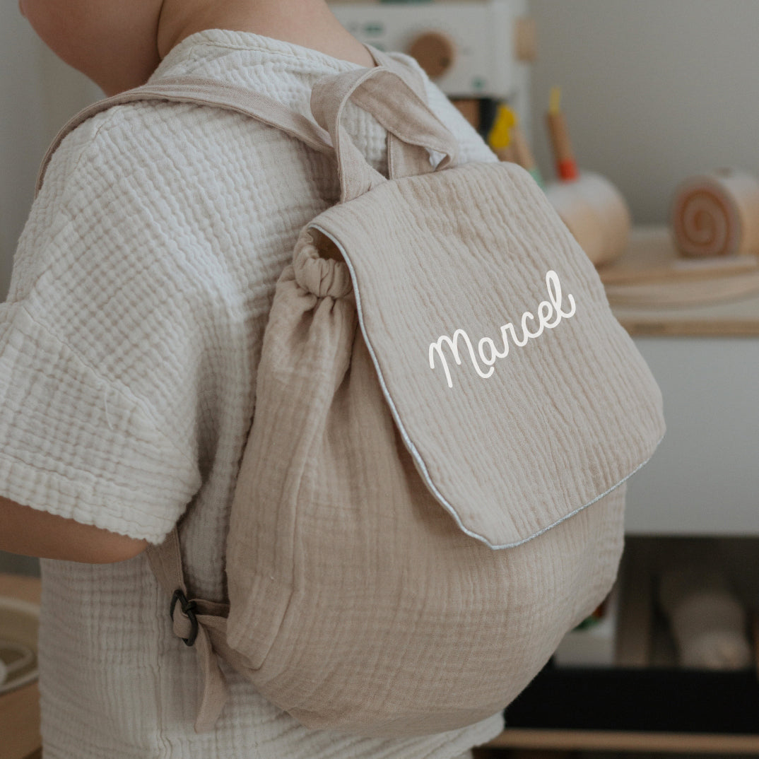 Sac à dos maternelle personnalisé beige porté par un enfant, bretelles réglables, pratique pour la crèche.