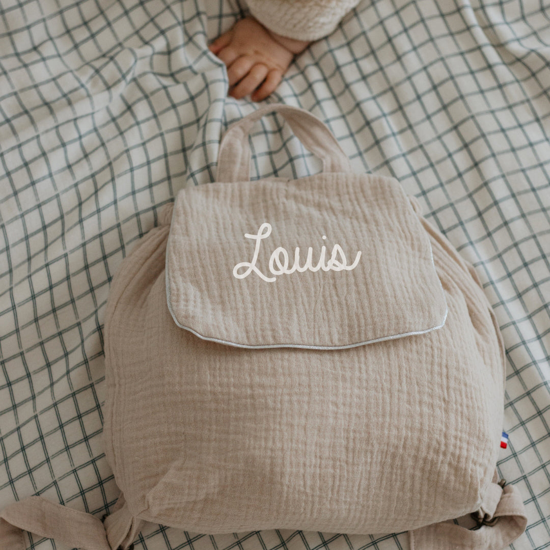 Sac à dos maternelle personnalisé en double gaze beige, sans motif sous le prénom, look épuré.