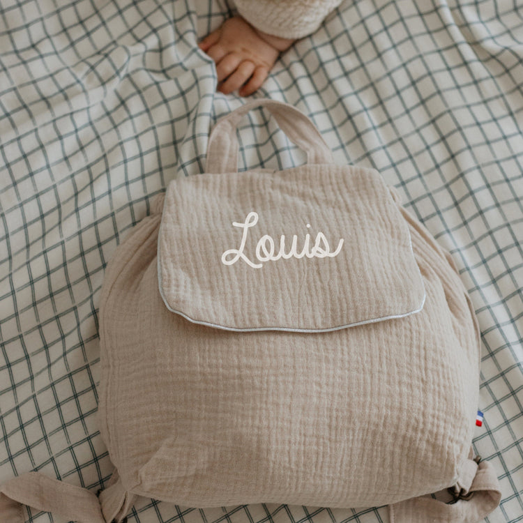 Sac à dos maternelle personnalisé en double gaze beige, sans motif sous le prénom, look épuré.