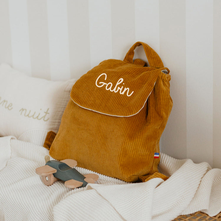 Sac à dos maternelle personnalisé en velours côtelé moutarde photo ambiance chambre enfant.