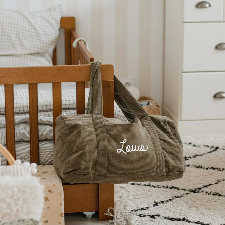 Sac week-end bébé personnalisé porté à l’épaule, pratique pour les déplacements.