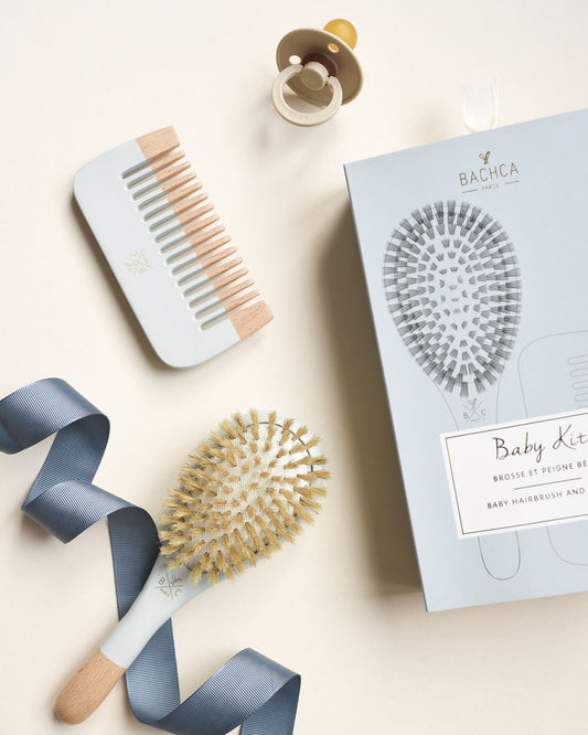 Coffret baby hair kit bleu, brosse et peigne en bois naturel pour bébé.  Bois et bleu pâle satiné sur la moitié du peigne et de la brosse. Coffret cartonné chic et élégant avec dessin du contenu du set brosse bébé. Bachca Paris.