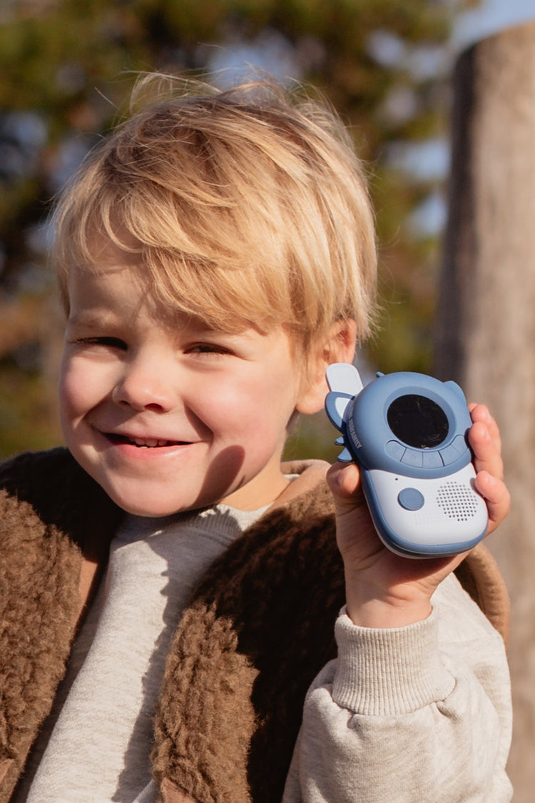 Petit garçon souriant qui écoute son talkie-walkie Raton laveur en plein air
