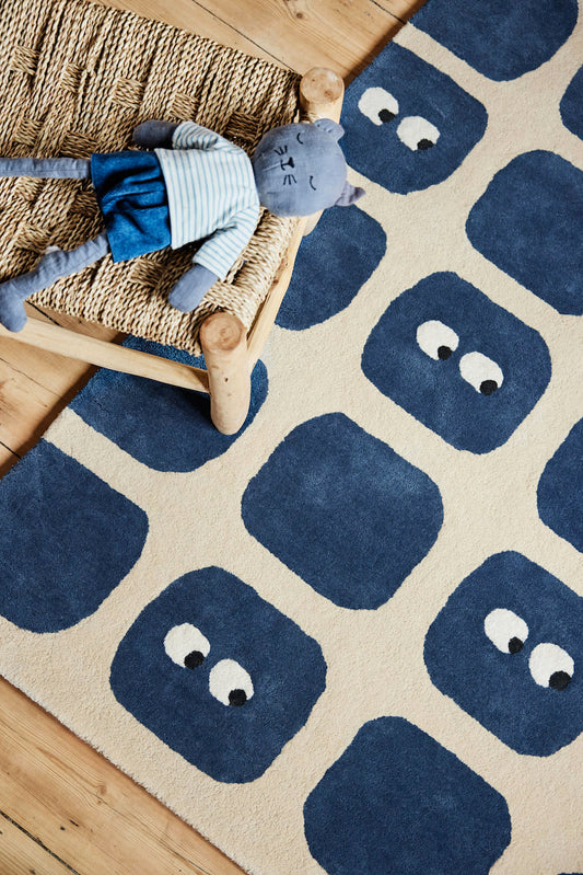 Tapis original pour chambre bébé garçon. En coton bio certifié GOTS. Sur fond beige, formes géométriques bleu dont certaines avec de petits yeux amusants. Une création originale de la marque française Bleuu-studio.